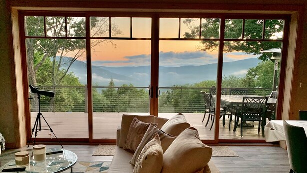 Una habitación con sofá, un telescopio y una mesa con sillas.