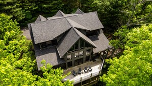 Ein zweigeschossiges Haus mit einem steilen Dach, umgeben von üppigen, grünen Bäumen.