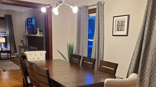 A dining area with a wooden table and chairs, a chandelier, and a fireplace. - Midway between Saratoga Springs and Lake George (Glens Falls)