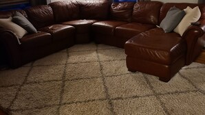 A living room with a brown leather sectional sofa, a lamp, and a framed picture on the wall. - Midway between Saratoga Springs and Lake George (Glens Falls)