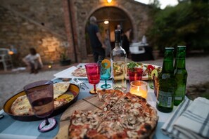 A table with pizzas, drinks, and a candle.