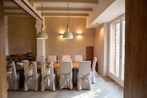 A dining area with a wooden table, white chairs, and two pendant lights.