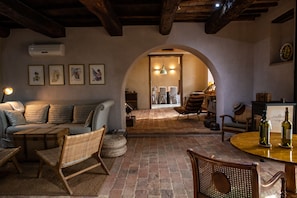 A cozy living area with a sofa, chairs, a wooden table, and a wine rack.