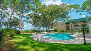 A swimming pool surrounded by lounge chairs and umbrellas, with a building in the background. - The Zen Place<br>Weekly and Monthly discount (Hilton Head Island)
