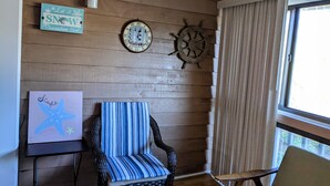 A room with a wooden wall, a clock, a starfish artwork, and a striped chair. - The Zen Place<br>Weekly and Monthly discount (Hilton Head Island)