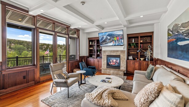 A spacious living room with a fireplace, large windows, and a view of the outdoors.