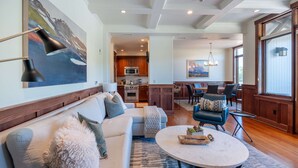 A spacious living room with a large sofa, a round coffee table, and a view into the kitchen area.
