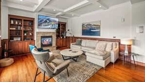 A living room with a fireplace, a television, a sofa, a coffee table, and a bookshelf.
