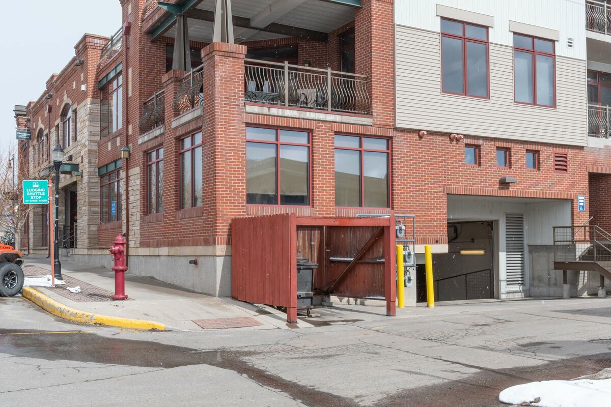 A multi-story building with a brick facade, a fire hydrant, a yellow curb, and a red fire truck parked on the street.