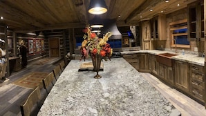 Une cuisine avec des meubles en bois, un plan de travail en granit et un îlot central agrémenté d’un vase de fleurs.
