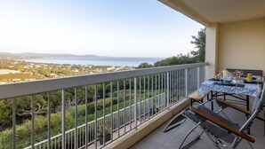 A balcony with a table set for dining, overlooking a scenic view of a coastal landscape. - Les Coccinelles by Interhome (Cavalaire)