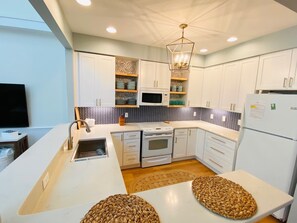 new kitchen with open shelving and fully stocked with basic supplies as well.