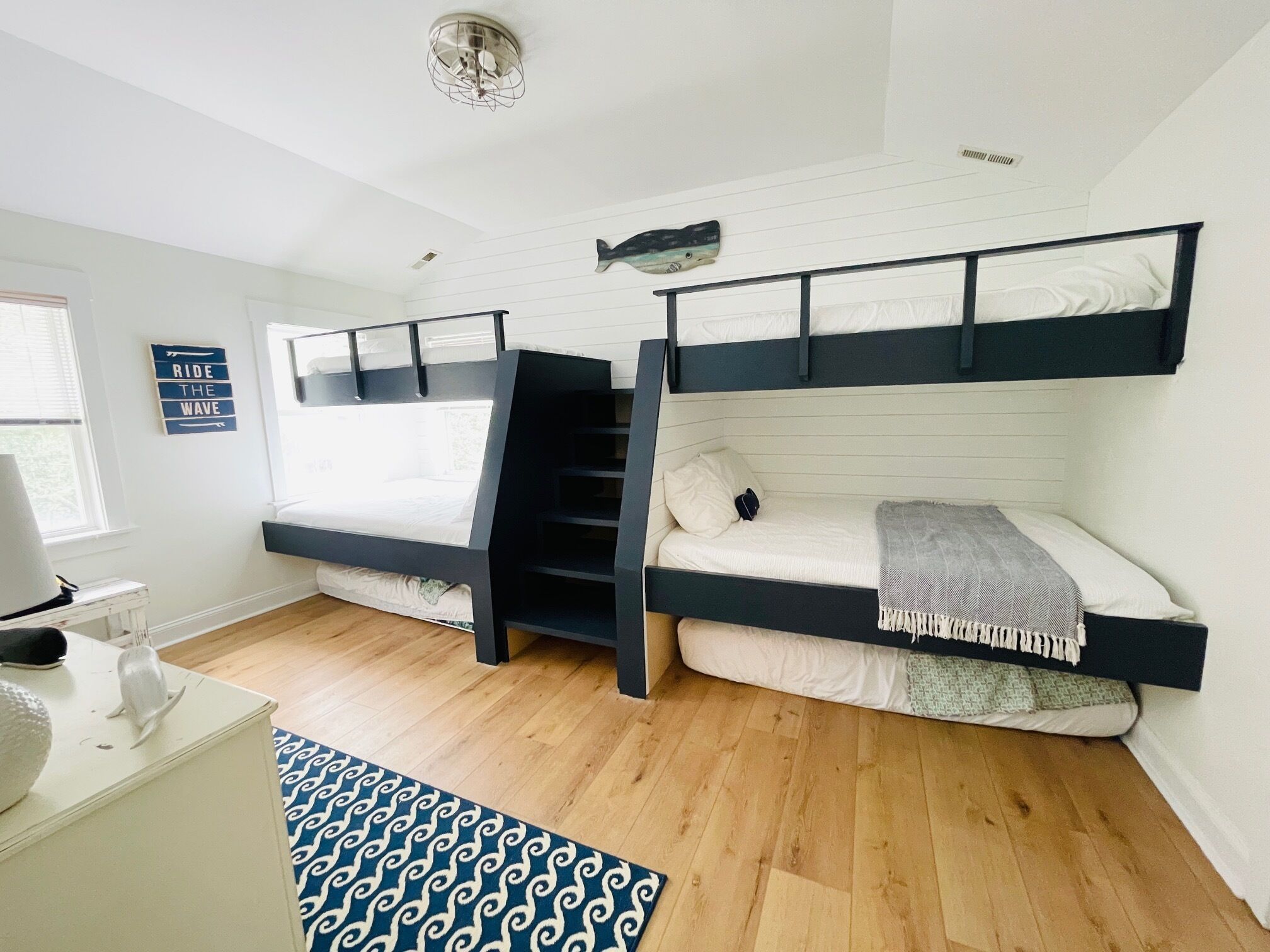 A room with two bunk beds, a small desk, and a window.