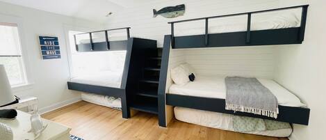 A room with two bunk beds, a small desk, and a window.