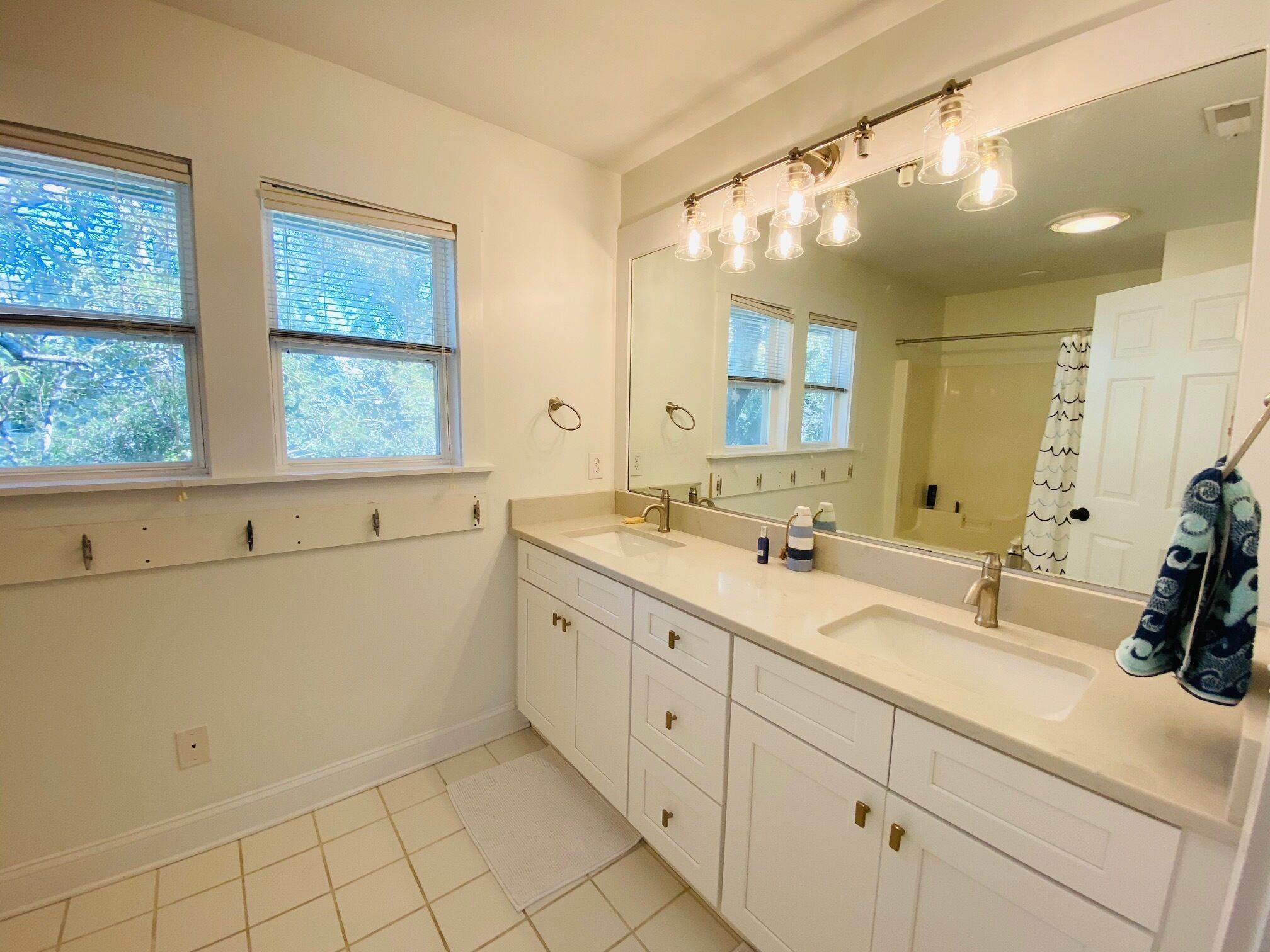 Une salle de bain avec deux lavabos, un grand miroir et un porte-serviettes.