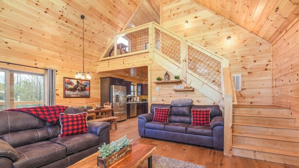 Ein geräumiger Wohnbereich mit zwei Sofas, einem Holztisch und einer Treppe, die in ein Obergeschoss führt.
