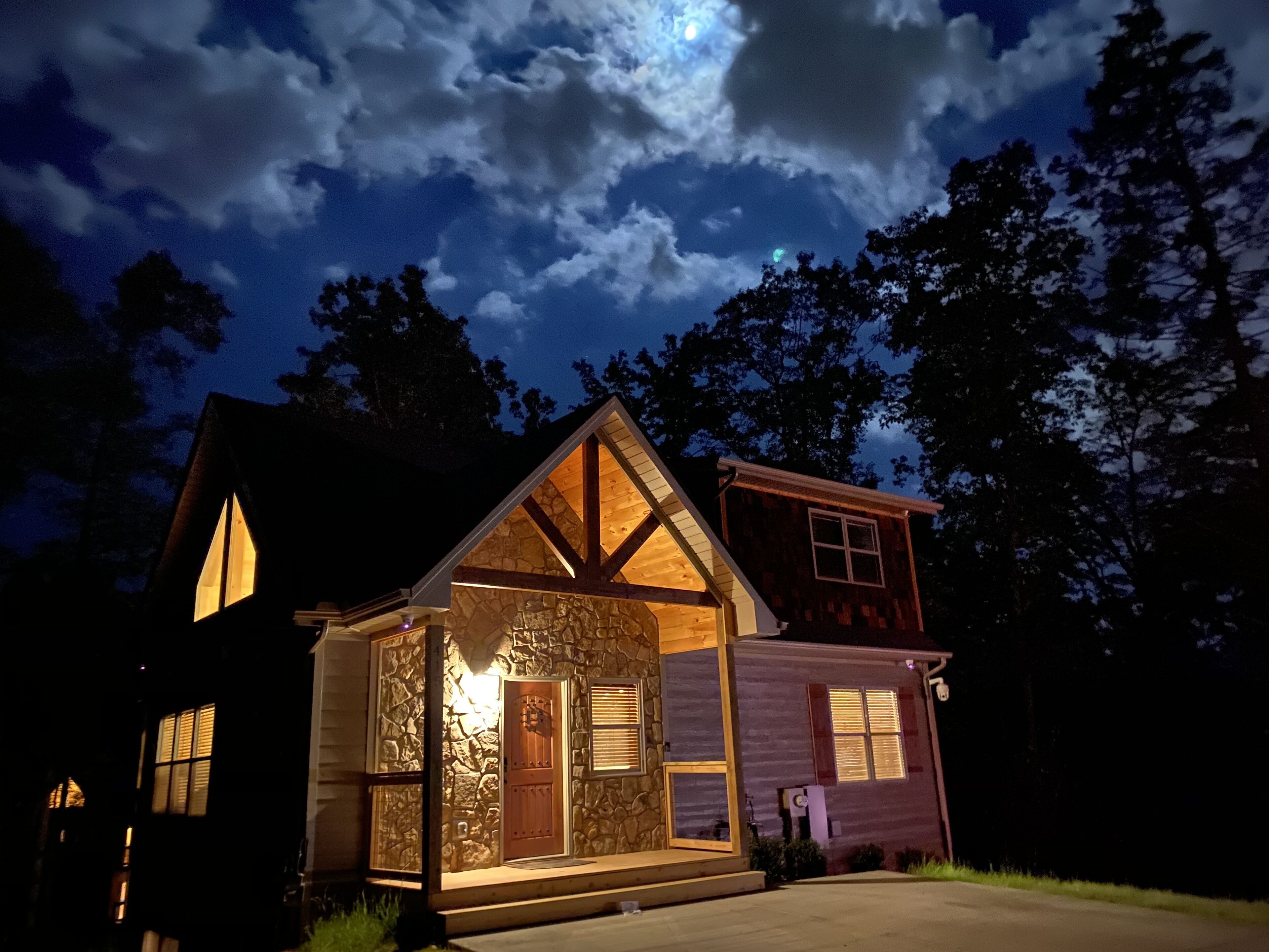 Une maison à deux étages avec une façade en pierre, un niveau supérieur en bois et un porche avant bien visible.