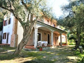 A two-story stone house with a covered patio and outdoor seating area. - Vacation home Marie by Interhome (Badesi)