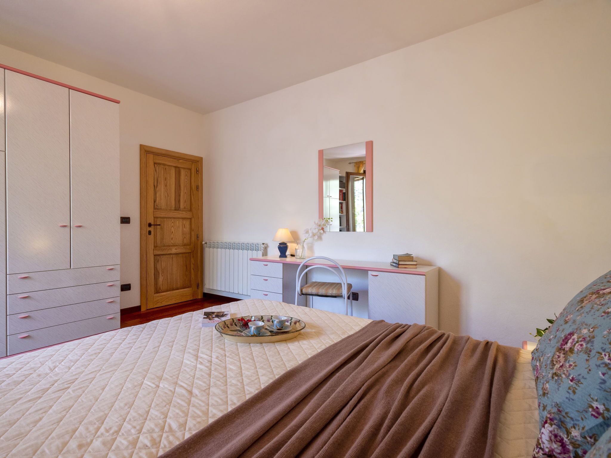 A bedroom with a bed, a desk, a wardrobe, and a mirror.