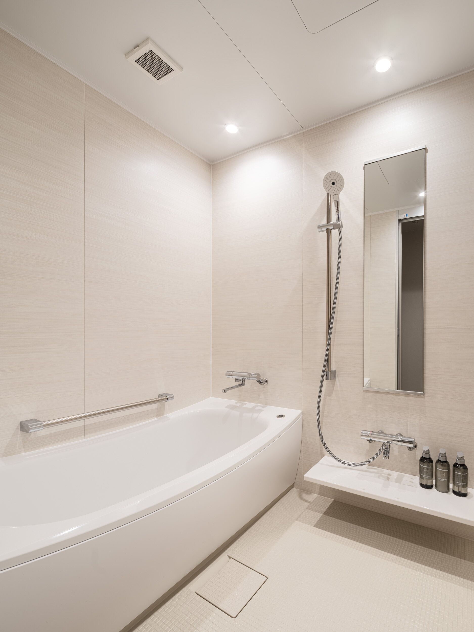 A modern bathroom with a freestanding bathtub, a showerhead, a handheld shower, and a vanity with toiletries.