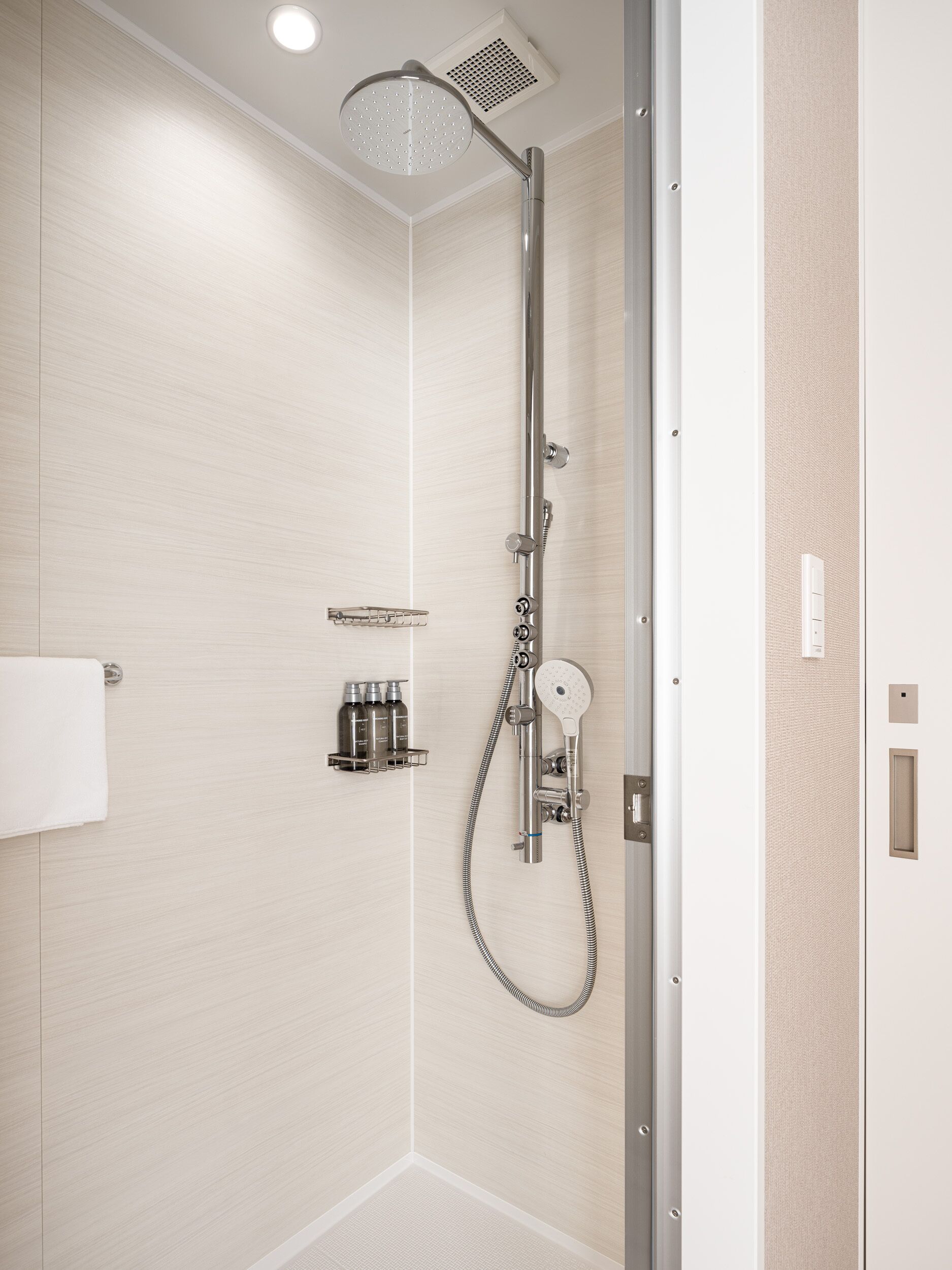 A modern shower with a handheld showerhead and a wall-mounted faucet.
