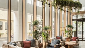 A spacious lobby with high ceilings, large windows, and a variety of seating arrangements including sofas and chairs. - Nest Hotel Naha Kumoji (Naha)