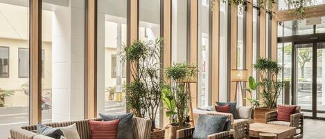 A spacious lobby with high ceilings, large windows, and a variety of seating arrangements including sofas and chairs.