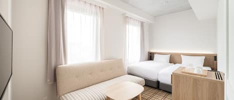 Habitación de hotel con sofá, una mesita, cama y un escritorio de madera con bandeja.