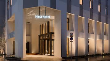 A modern hotel entrance with a glass door and a sign reading "Nest hotel".