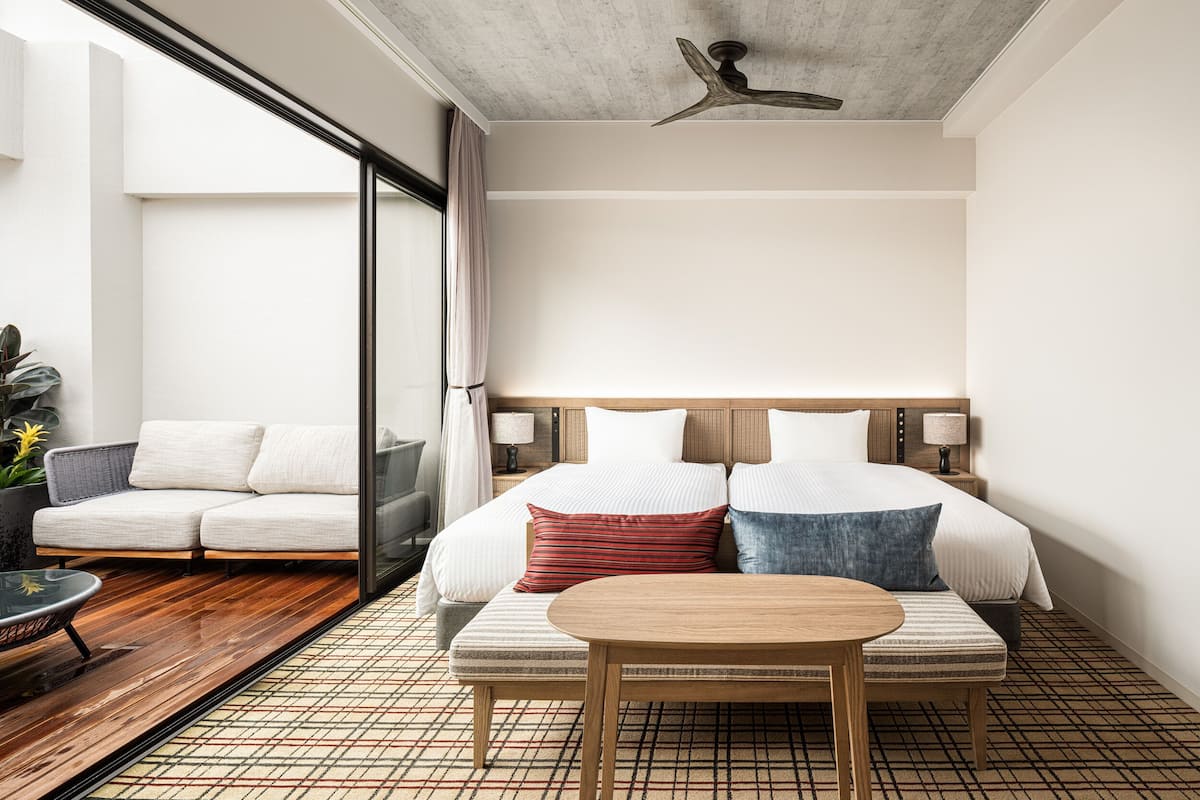 A modern hotel room with a large bed, a wooden table, and a sofa.