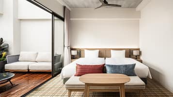 A modern hotel room with a large bed, a wooden table, and a sofa.