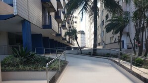 A modern urban walkway with a tiled floor, metal railings, and a row of buildings with balconies. - Ed. Fte. Gonzaga beach 14and sea view (Santos)