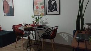 Een eetruimte met een ronde tafel, twee stoelen, een schaal met snacks en een potplant.