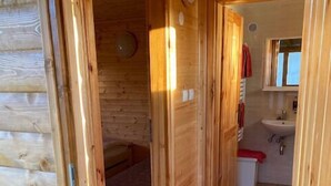 A wooden interior with a visible bathroom including a sink and toilet.