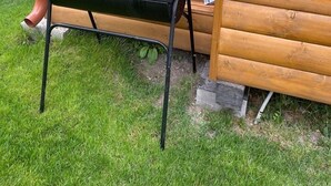 A black barbecue grill on a grassy lawn next to a wooden structure.