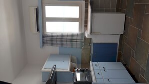 A compact kitchen with a window, a built-in oven, and a microwave.