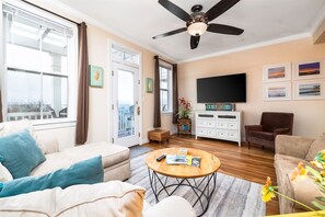 A living room with a ceiling fan, a flat-screen TV, a coffee table, and a sofa.