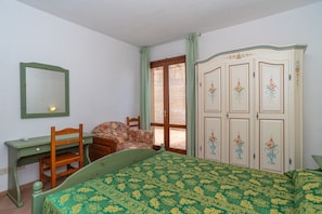 Une chambre à coucher avec un lit, un bureau, une chaise, une armoire et une fenêtre.