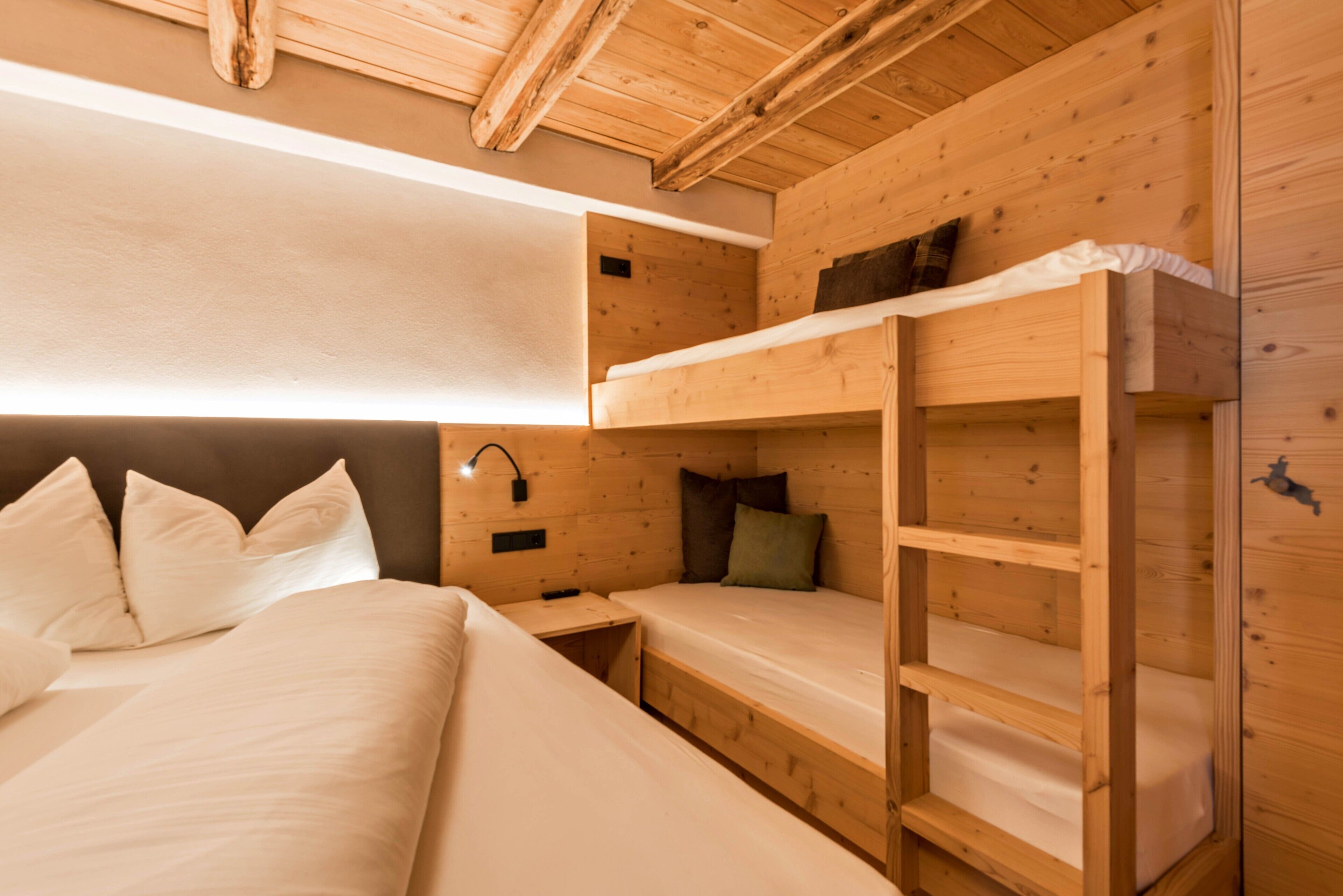 Una habitación estilo cabaña de madera con literas, una mesita de noche y una lámpara de pared.