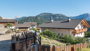 Ein Bergdorf mit traditionellen Holzhäusern, einem Holzzaun und freiem Blick auf die umliegenden Berge.