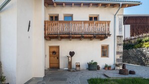 Un bâtiment doté d’un balcon en bois, d’une entrée pavée de pierres et d’une porte rustique.