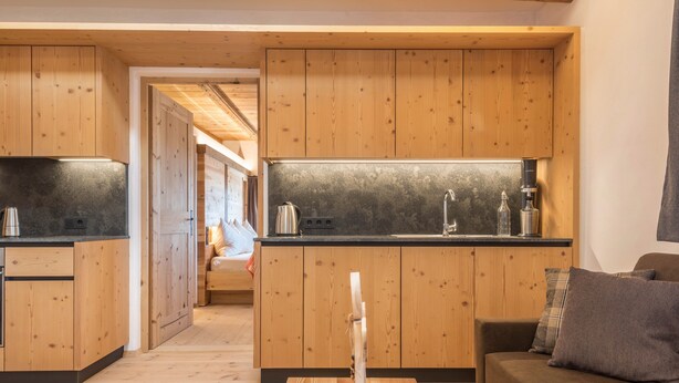Une cuisine moderne avec des meubles en bois, un plan de travail noir et un îlot central doté d’une bouilloire.