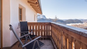 Une terrasse en bois offrant une vue sur des montagnes enneigées.