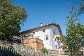 Un bâtiment blanc doté d’un balcon en bois et d’un mur en pierre.