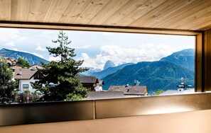 A room with a large window overlooking a mountainous landscape.