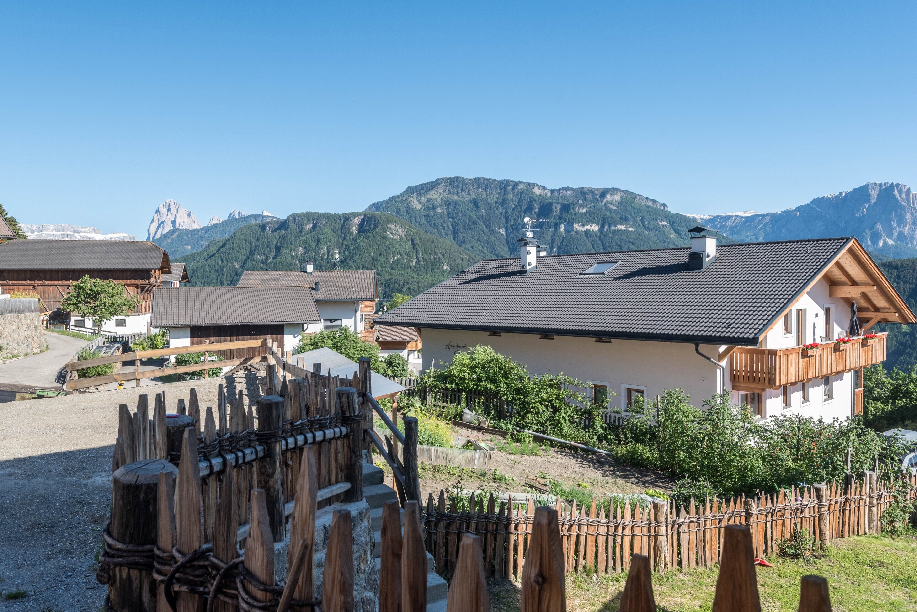 Een landelijk bergdorp met traditionele houten huizen, een houten hek en een helder uitzicht op de omliggende bergen.