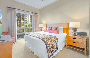 Habitación de hotel con una cama grande, un escritorio con una computadora portátil, una mesita de noche con una lámpara y vistas a un edificio a través de la ventana.