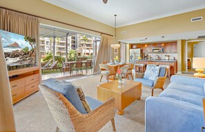 A hotel room with a balcony, dining area, kitchen, and seating arrangement.