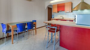 A modern kitchen with a central island, blue chairs, and a red accent wall.