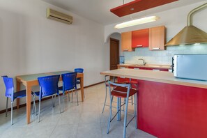 Una cocina moderna con una isla central, sillas azules y una pared de acento roja.